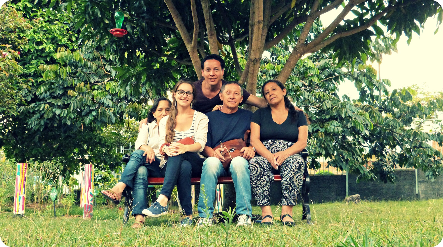 Charlène, Charles, sus padres y una prima a la sombra de un árbol y sentados en una banca en el jardín del Museo del Oro de Armenia