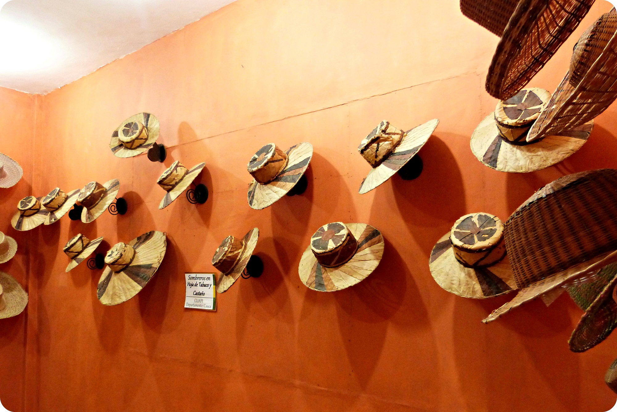Sombreros presentandos en una pared naranja, en el museo nacional del sombrero en la casa de la cultura en Aguadas