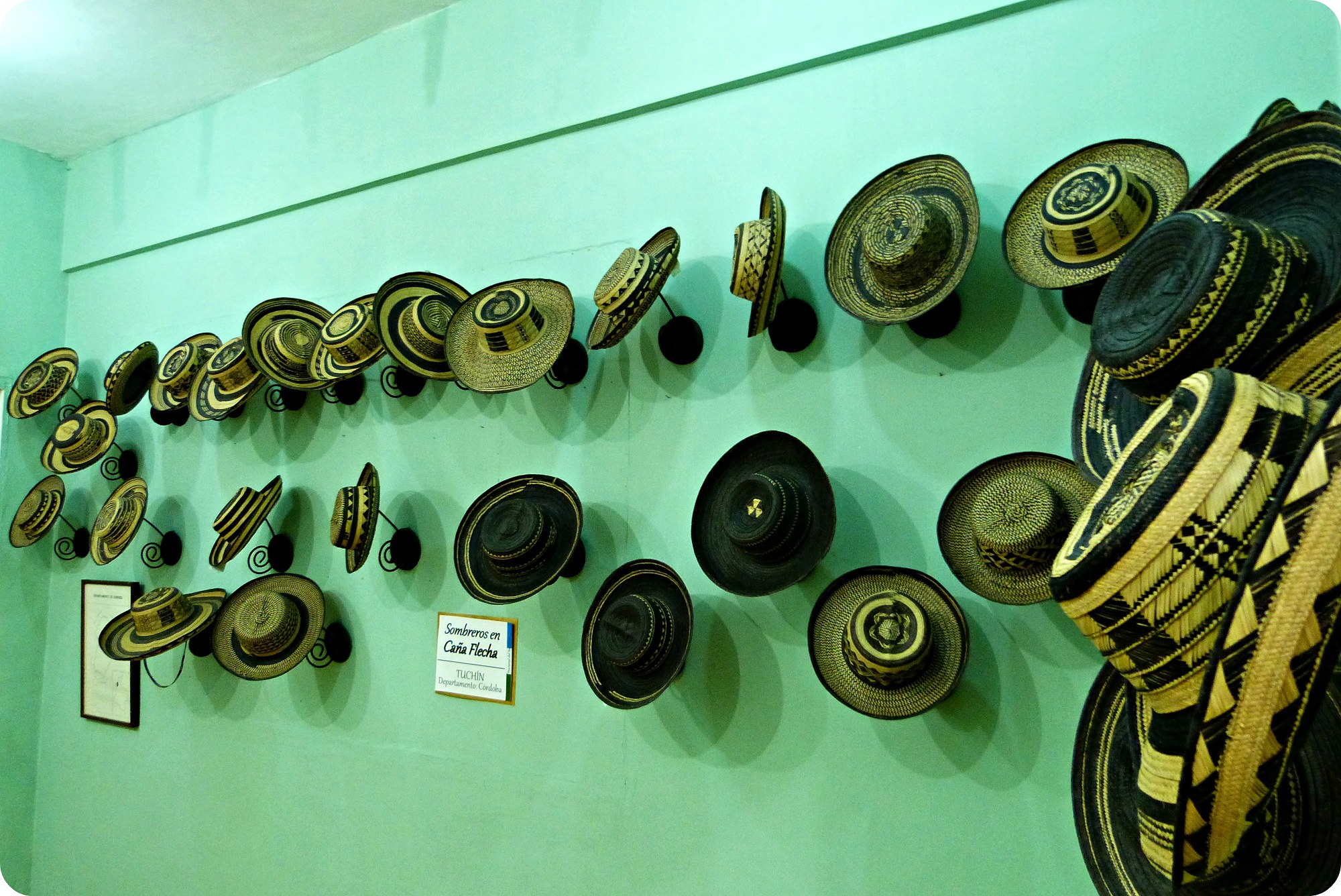 Sombreros presentados en una pared verde, en el museo nacional del sombrero en la casa de la cultura en Aguadas