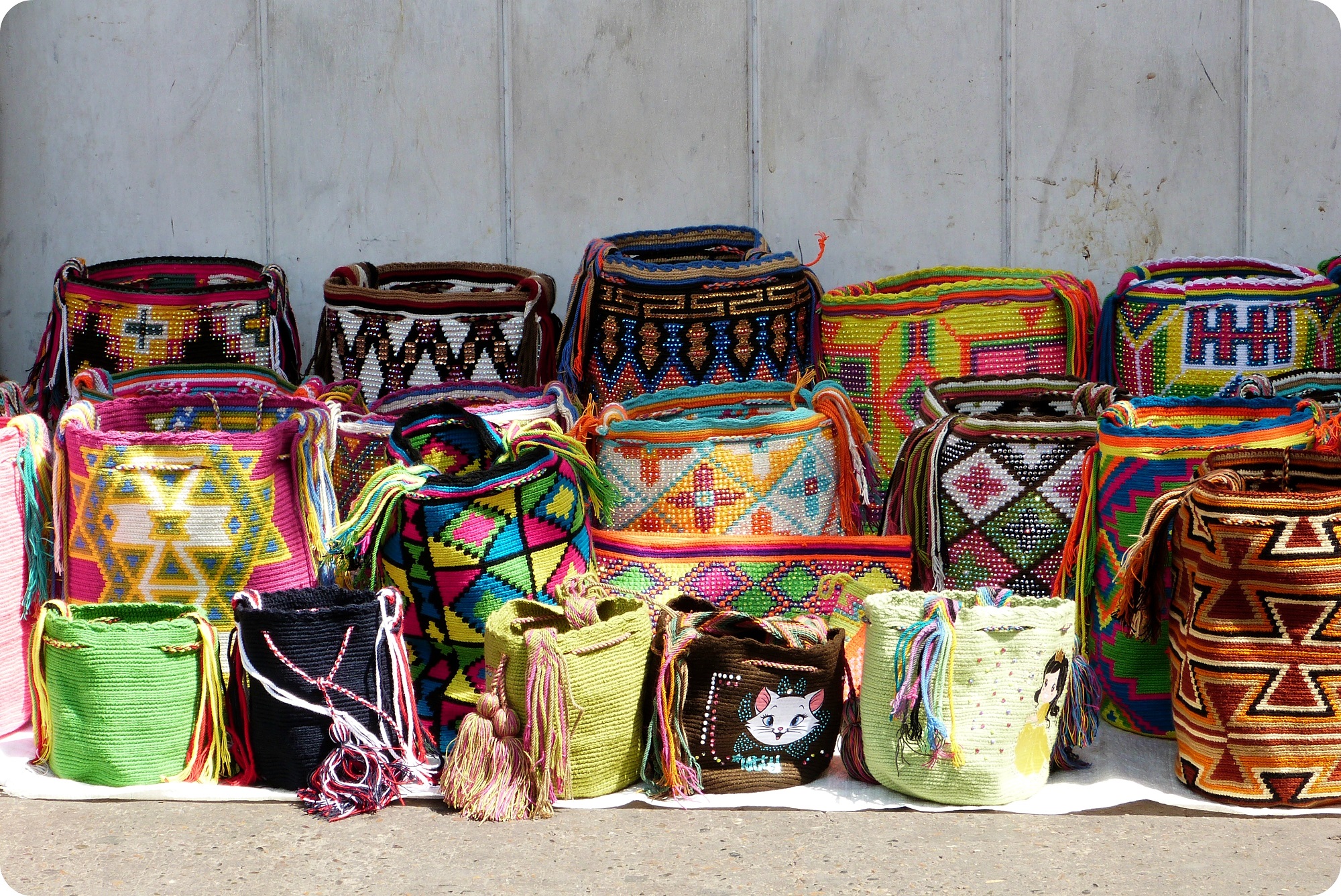 Mochilas de todos los colores fabricados por la población Wayuu expuestas a lo largo de un edificio del centro de Cartagena
